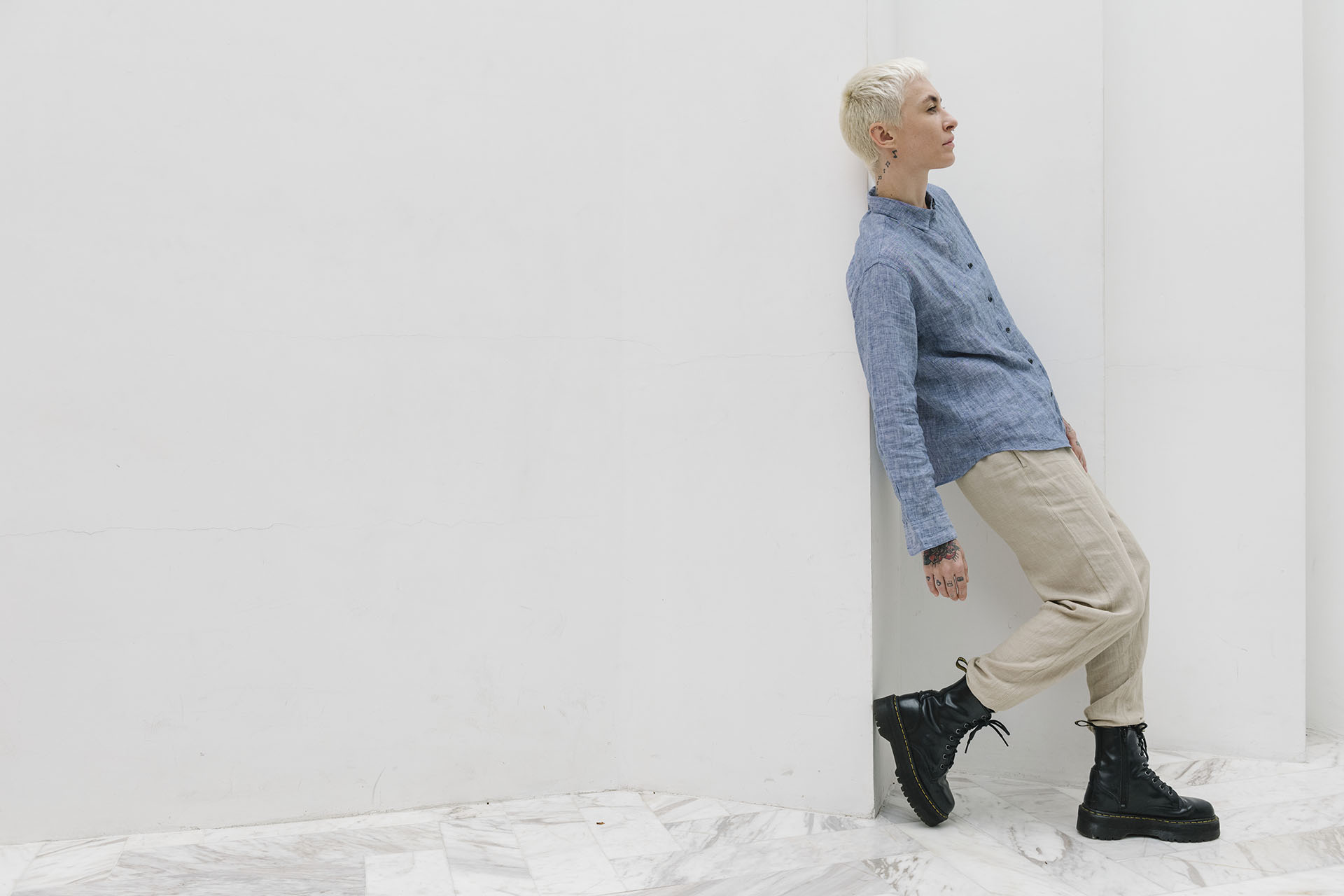 Woman wearing combat boots casually standing by a wall