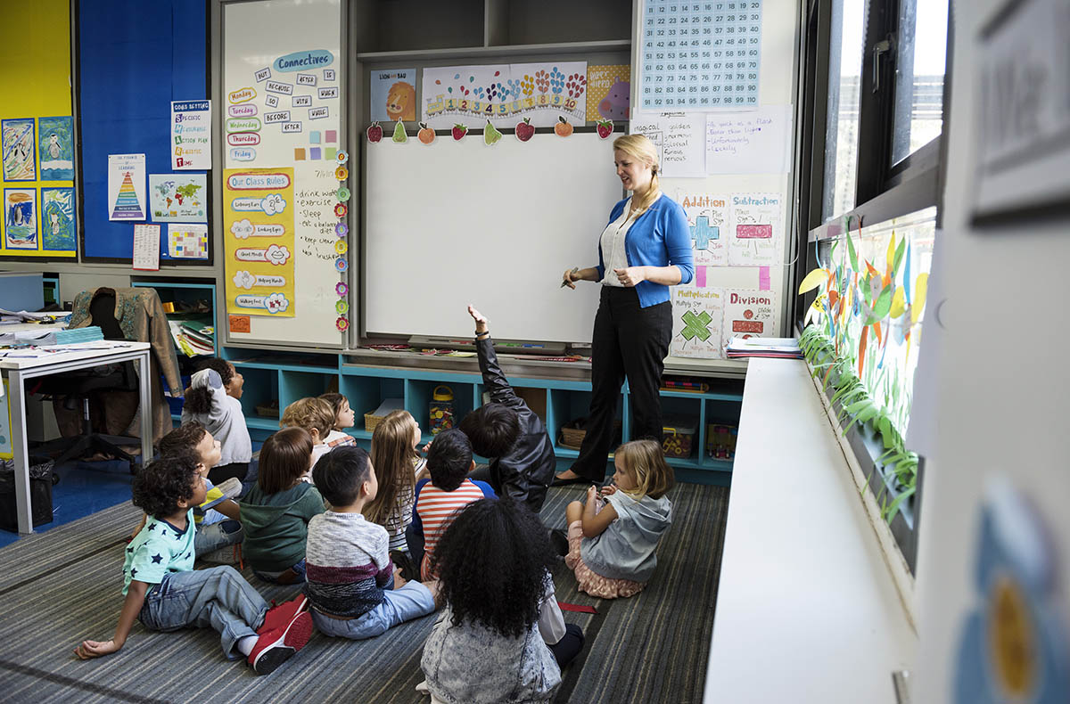 Kindergarten students sitting on the floor listening to teacher